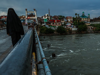 A woman is wearing a Burqa (Hijab) and walking on a bridge after light rainfall in Sopore, Jammu and Kashmir, India, on June 12, 2024. (