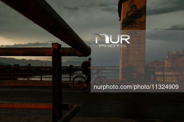 A boy is riding a bicycle during sunset after rainfall in Sopore, Jammu and Kashmir, India, on June 12, 2024 