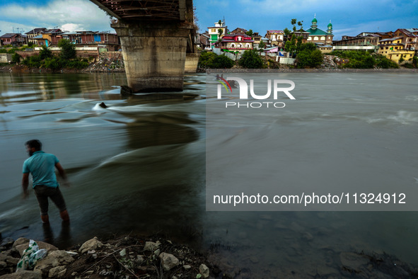 A boy is standing near River Jhelum during sunset after light rainfall in Sopore, Jammu and Kashmir, India, on June 12, 2024 