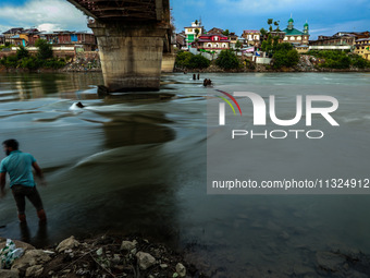 A boy is standing near River Jhelum during sunset after light rainfall in Sopore, Jammu and Kashmir, India, on June 12, 2024 (