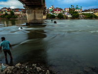 A boy is standing near River Jhelum during sunset after light rainfall in Sopore, Jammu and Kashmir, India, on June 12, 2024 (