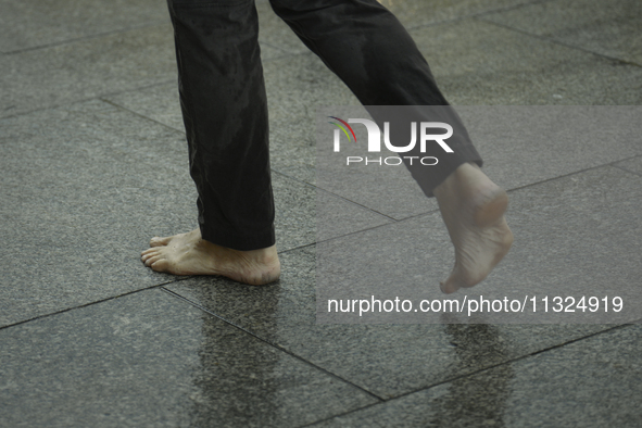 A man walks barefoot during a rain storm in Warsaw, Poland on 02 June, 2024. 