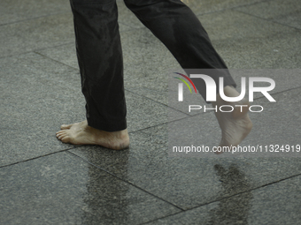 A man walks barefoot during a rain storm in Warsaw, Poland on 02 June, 2024. (