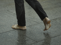 A man walks barefoot during a rain storm in Warsaw, Poland on 02 June, 2024. (