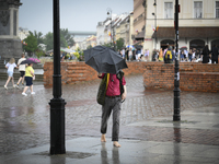 A man with an umbrella is seen walking barefoot during a rain storm in Warsaw, Poland on 02 June, 2024. (