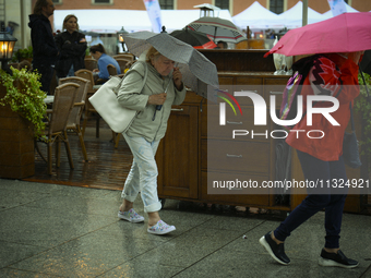 People are seen sheltering from a sudden downpour in Warsaw, Poland on 02 June, 2024. (