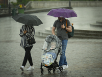 People with a child in a buggy are seen sheltering from a sudden downpour in Warsaw, Poland on 02 June, 2024. (