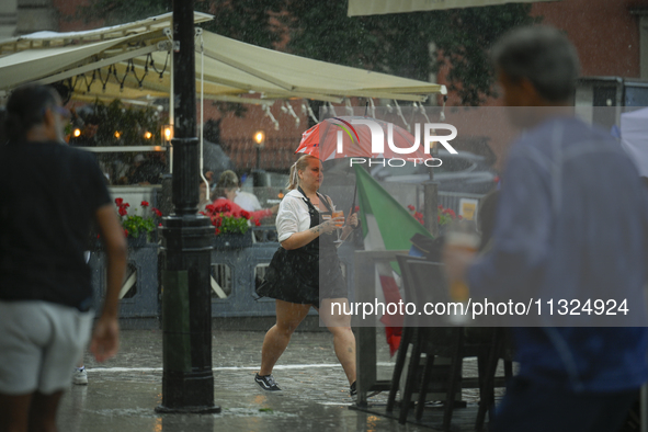 A waitress carrying coffee and rinks is seen during a sudden downpour in Warsaw, Poland on 02 June, 2024. 