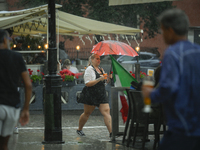 A waitress carrying coffee and rinks is seen during a sudden downpour in Warsaw, Poland on 02 June, 2024. (