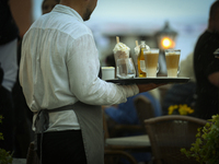 A waiter carrying coffee and rinks is seen during a sudden downpour in Warsaw, Poland on 02 June, 2024. (