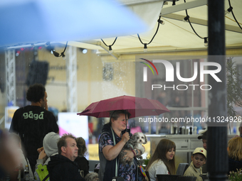 People shelter at a restaurant from a sudden downpour in Warsaw, Poland on 02 June, 2024. (