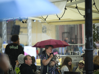 People shelter at a restaurant from a sudden downpour in Warsaw, Poland on 02 June, 2024. (