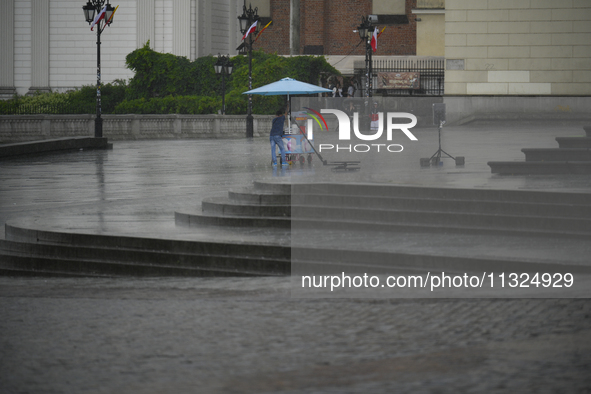 A worker shelters from the rain in Warsaw, Poland on 02 June, 2024. 