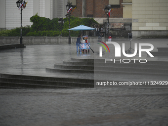 A worker shelters from the rain in Warsaw, Poland on 02 June, 2024. (