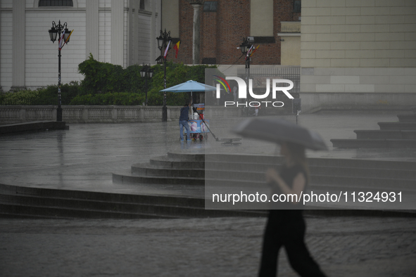 People are seen sheltering from a sudden downpour in Warsaw, Poland on 02 June, 2024. 