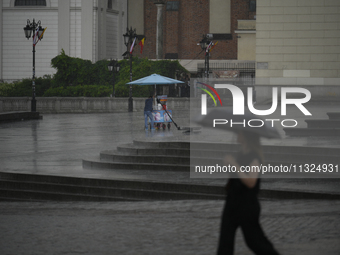 People are seen sheltering from a sudden downpour in Warsaw, Poland on 02 June, 2024. (