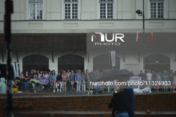 People are seen sheltering from a sudden downpour in Warsaw, Poland on 02 June, 2024. 