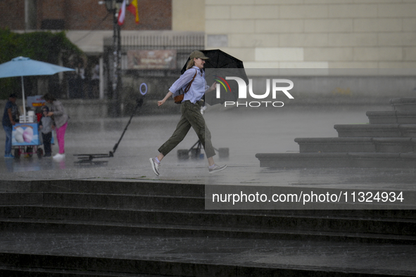 People are seen sheltering from a sudden downpour in Warsaw, Poland on 02 June, 2024. 