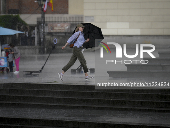 People are seen sheltering from a sudden downpour in Warsaw, Poland on 02 June, 2024. (