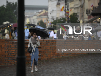 People are seen sheltering from a sudden downpour in Warsaw, Poland on 02 June, 2024. (