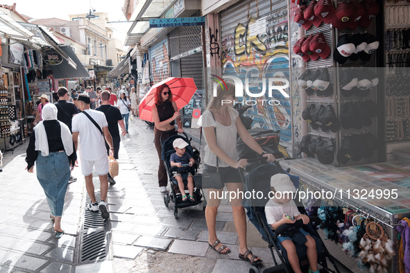 A woman with her child is holding an umbrella to protect from the sun near Monastiraki square during a heatwave in Athens, Greece, on June 1...