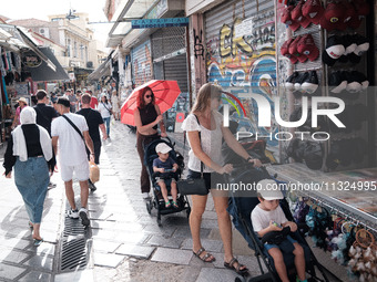 A woman with her child is holding an umbrella to protect from the sun near Monastiraki square during a heatwave in Athens, Greece, on June 1...