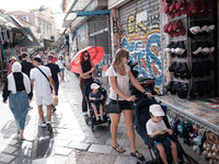 A woman with her child is holding an umbrella to protect from the sun near Monastiraki square during a heatwave in Athens, Greece, on June 1...