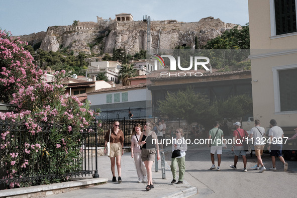 Tourists are walking in front of Acropolis Hill near Monastiraki Square during a heatwave in Athens, Greece, on June 12, 2024. Many of the c...