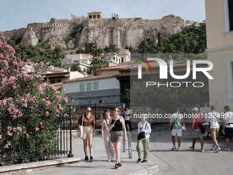 Tourists are walking in front of Acropolis Hill near Monastiraki Square during a heatwave in Athens, Greece, on June 12, 2024. Many of the c...