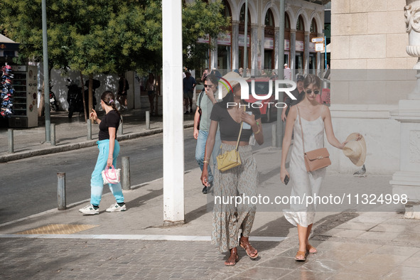 A woman is wearing a hat to protect from the sun near Monastiraki Square during a heatwave in Athens, Greece, on June 12, 2024. Many of the...