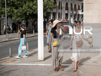 A woman is wearing a hat to protect from the sun near Monastiraki Square during a heatwave in Athens, Greece, on June 12, 2024. Many of the...