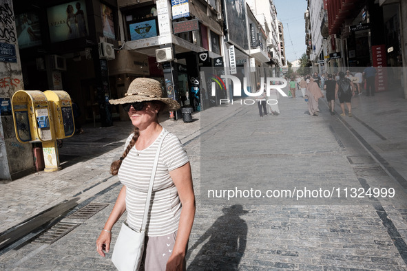 A woman is wearing a hat to protect from the sun near Monastiraki Square during a heatwave in Athens, Greece, on June 12, 2024. Many of the...