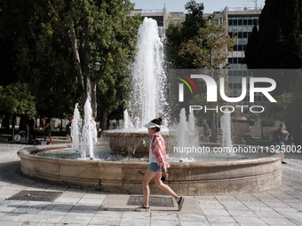 A woman is wearing a hat to protect from the sun at Syntagma Square during a heatwave in Athens, Greece, on June 12, 2024. Many of the count...