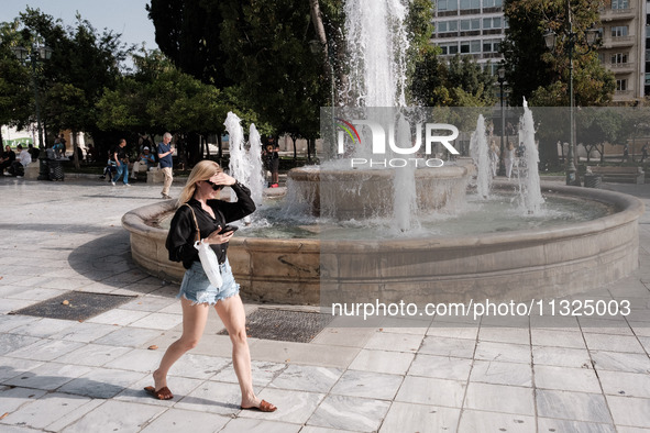 A woman is putting her hand on her forehead to protect from the sun at Syntagma Square during a heatwave in Athens, Greece, on June 12, 2024...