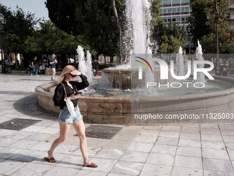 A woman is putting her hand on her forehead to protect from the sun at Syntagma Square during a heatwave in Athens, Greece, on June 12, 2024...