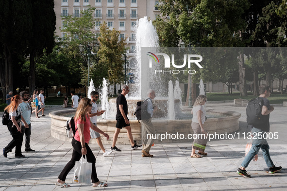 Tourists are walking in front of a fountain at Syntagma Square during a heatwave in Athens, Greece, on June 12, 2024. Many of the country's...