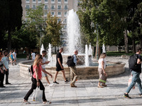 Tourists are walking in front of a fountain at Syntagma Square during a heatwave in Athens, Greece, on June 12, 2024. Many of the country's...