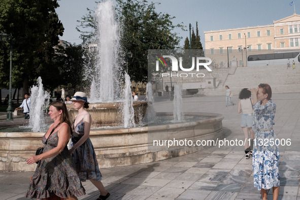 Tourists are walking in front of a fountain at Syntagma Square during a heatwave in Athens, Greece, on June 12, 2024. Many of the country's...