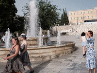 Tourists are walking in front of a fountain at Syntagma Square during a heatwave in Athens, Greece, on June 12, 2024. Many of the country's...