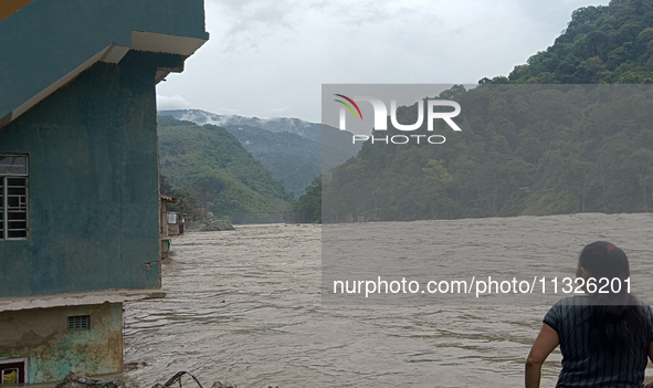 Residents are standing at the river banks of Teesta River to see the risen water level of the river, which flows beside National Highway 10,...