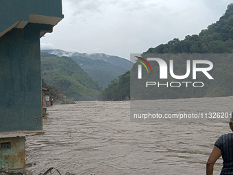 Residents are standing at the river banks of Teesta River to see the risen water level of the river, which flows beside National Highway 10,...