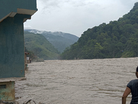 Residents are standing at the river banks of Teesta River to see the risen water level of the river, which flows beside National Highway 10,...