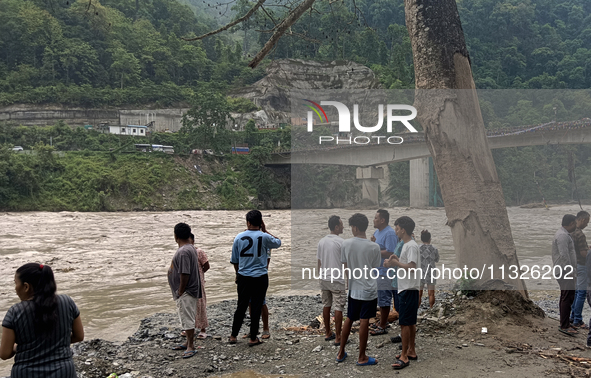 Residents are standing at the river banks of Teesta River to see the risen water level of the river, which flows beside National Highway 10,...