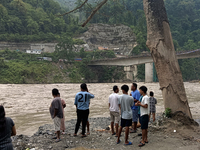 Residents are standing at the river banks of Teesta River to see the risen water level of the river, which flows beside National Highway 10,...