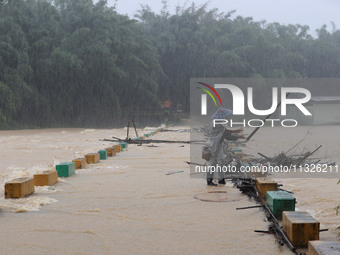 A villager is braving the rain to clear a tree branch stuck on a bridge in Dantan Township, Rongan County, Liuzhou, China, on June 13, 2024....