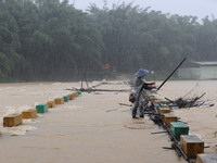 A villager is braving the rain to clear a tree branch stuck on a bridge in Dantan Township, Rongan County, Liuzhou, China, on June 13, 2024....