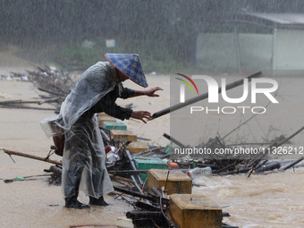 A villager is braving the rain to clear a tree branch stuck on a bridge in Dantan Township, Rongan County, Liuzhou, China, on June 13, 2024....