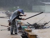 A villager is braving the rain to clear a tree branch stuck on a bridge in Dantan Township, Rongan County, Liuzhou, China, on June 13, 2024....