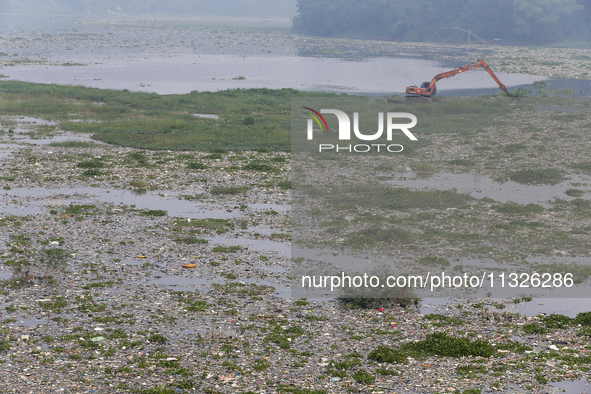 Officers are using an excavator to clean up plastic waste that has settled in the Citarum River in Batujajar, Bandung, West Java, Indonesia,...