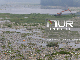 Officers are using an excavator to clean up plastic waste that has settled in the Citarum River in Batujajar, Bandung, West Java, Indonesia,...